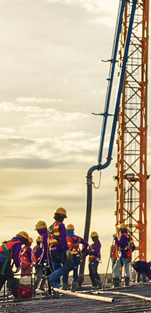 Construction crew working beneath a tower crane at sunset